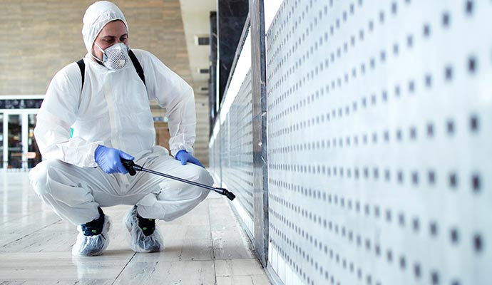 A person is using a spray tool to apply disinfectant to a surface.