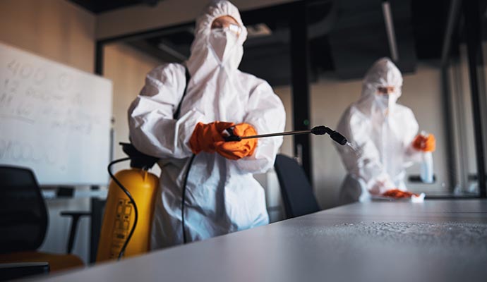 Two individuals disinfecting the table surface using disinfectants spary.