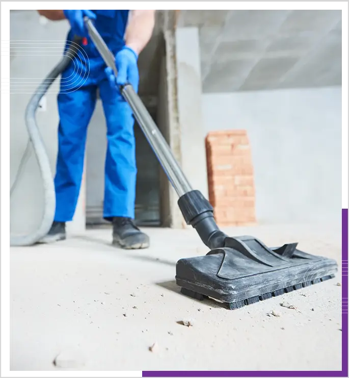 A person engaged in construction cleanup, using an industrial vacuum cleaner