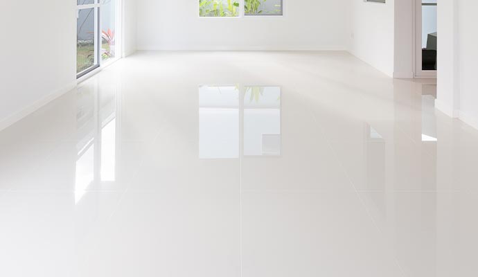 A spacious room with a clean, glossy white tiled floor.